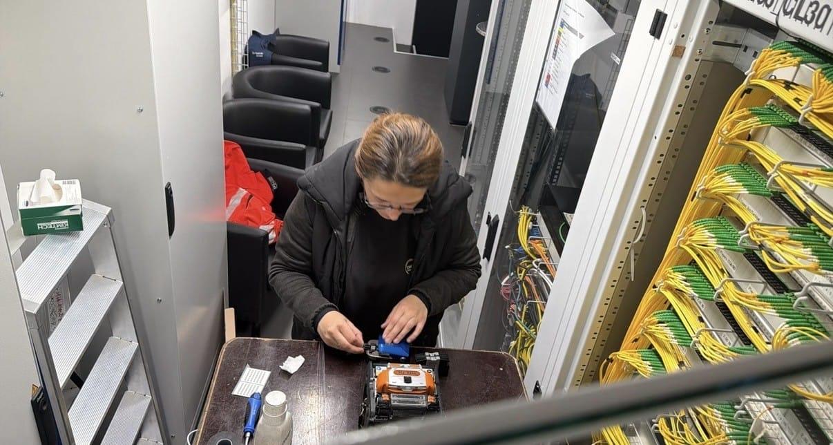Technikerin spleisst Glasfasern an einem Arbeitsplatz vor einem Verteilerschrank in der Swiss Life Arena